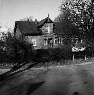 Steinfeld: Kreisstraße Richtung Reinfeld: vorn rechts Straßenschild: dahinter Wohnhaus [ehemalige Volksschule] mit Garten und Hecke: hinten rechts Baum