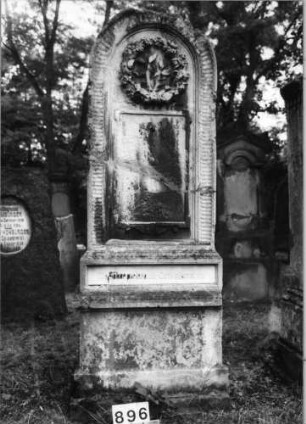 Grabstein 896 (Index: 99630388) Material: Sandstein Zustand: stark verwittert, gebrochen, repariert Maße HxBxT: 192x72x32 cm Beschreibung: Stele auf Sockel mit Runbdogenabschluß, Schriftfeld rechteckig Symbolik: Blumenkranz, umlaufendes Fries: Grabstein 896