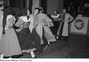 Auftritt einer am Bezirksausscheid der Volkskunstgruppen 1954 teilnehmenden Tanzgruppe, im Hintergrund Instrumentalisten
