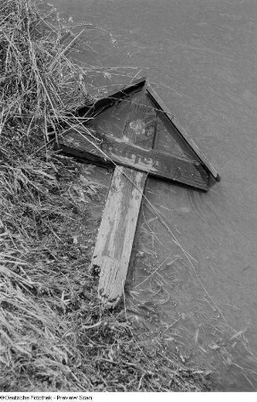 An ein Ufer geschwemmtes Grabkreuz