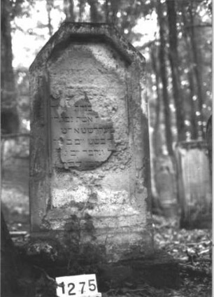 Grabstein 1275 (Index: 99900109) Material: Sandstein Zustand: fast völlig verwittert Maße HxBxT: 136x60x19 cm Beschreibung: aufgesockelte Stele mit abgeflachtem Dreiecksabschluss: Grabstein 1275
