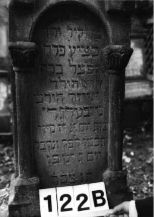 Grabstein 122 (Index: 100079731) Material: Sandstein Zustand: verwittert mit Textverlust Maße HxBxT: 130x36x23 cm Beschreibung: ädikularartige Stele mit Halbsäulen, Sockel, eingezogener Rundbogenabschluß mit Mittelakroter, Schriftfeld eingetieft Symbolik: Sternchen, Ranken Besonderheit: Kindergrab: Grabstein 122B