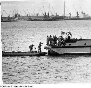 Deutschland . Nationale Volksarmee - Seestreitkräfte. Übergabe von Dienstmaterial zwischen einer Motorbarkasse und einem Kampfschiff in einem Hafen
