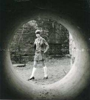 Porträt einer jungen Frau im Minirock, durch eine Röhre fotografiert