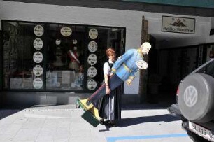 Sankt Wolfgang - Ladenbesitzerin : Eine Ladenbesitzerin stellt eine Werbefigur vor ihr Geschäft in Sankt Wolfgang, aufgenommen 2008