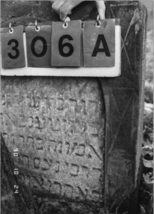 Grabstein 306 (Index: 100115865) Material: Sandstein Zustand: verwittert mit Textverlust, teilweise im Boden versunken Maße HxBxT: 92x61x15 cm Beschreibung: Stele mit giebelartigem Abschluß, eingetieftes Schriftfeld mit Rundbogenabschluß Symbolik: Cohanim-Hände: Grabstein 306A (Nachholaufnahme)