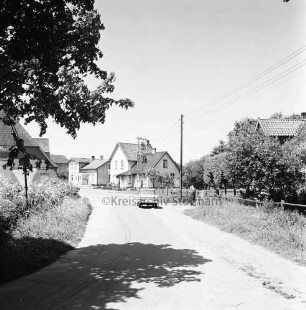 Dorfstraße: parkender Pkw, dahinter Wohngebäude