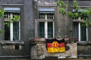 DDR. Staatsfahne am Balkon eines maroden Altbaus