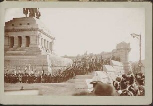 Ehrengäste, teils mit Fahnen, auf den Stufen zum Denkmal.