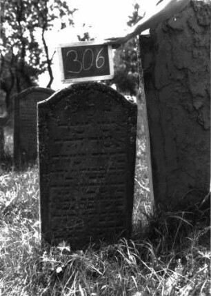 Grabstein 306 (Index: 100103131) Material: Sandstein Zustand: gut erhalten Maße HxBxT: 97x47x6 cm Beschreibung: Stele, Konvexbogenabschluss, Schriftfeld durch umlaufende Rille abgeteilt, im Bogen Levitenkanne Symbolik: Levitenkanne: Grabstein 306