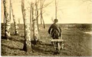 Mann mit Schubkarre am Waldrand