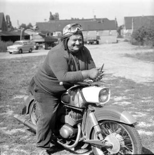 Mopedfahrer : Portraitaufnahme eines alten, kräftig gebauten Mopedfahrers, der auf seinem Moped, Bautyp Mz ES 150, sitzt und dem Betrachter/Fotografen freundlich anblinzeld, während er sich lässig auf den Lenker des Mopeds lehnt