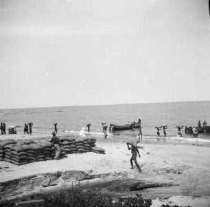 Ware am Strand : Kakao und Kaffeesäcke werden am Strand von Bata auf Boote verladen.