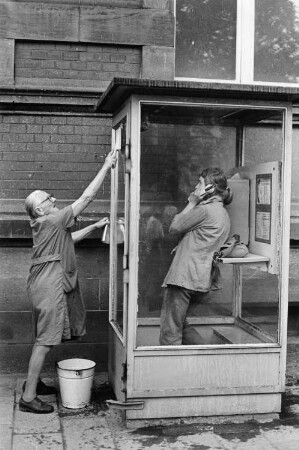 Jana Richter in einer Telefonzelle und alte Frau beim Saubermachen dieser Telefonzelle, aufgenommen in Gotha