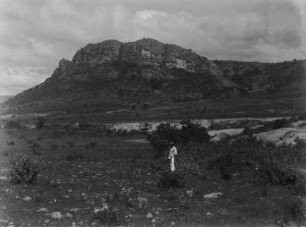 Mann vor einem Berg : Ein Mann in einer Gras- und Buschlandschaft vor einem Berg in Mexiko.