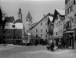 Kitzbühel in Tirol. Österreich. Verschneite Hauptstraße. Im Hintergrund die Türme der Stadtpfarrkirche "Zum Heiligen Andreas" (links) und der Liebfrauenkirche (rechts)