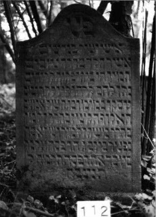 Grabstein 112 (Index: 99803094) Material: Sandstein Zustand: unten leicht verwittert Maße HxBxT: 113x66x10 cm Beschreibung: Stele mit Karniesbogen und profiliertem Rand Besonderheit: längerer Text, Endreim: Grabstein 112