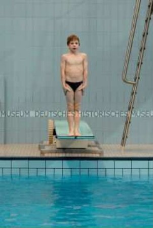 Junge auf dem Sprungbrett im Schwimmbad (Altersgruppe B)