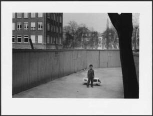 Junge mit Spielzeugauto an einem Baustellenzaun, Hamburg, St. Georg
