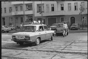 Ein Mann schiebt in Begleitung einer Funkstreife seinen defekten PKW Trabant von der Straße