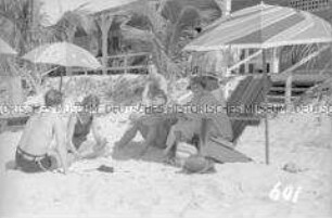 Touristen am Strand unter Sonnenschirmen