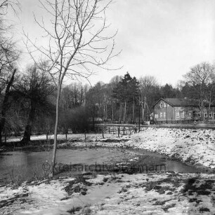 Lasbek-Gut: Lasbeker Mühlenteich: Blick nach Abriss der Lasbeker Mühle: im Hintergrund Gebäude zwischen Bäumen: Winter