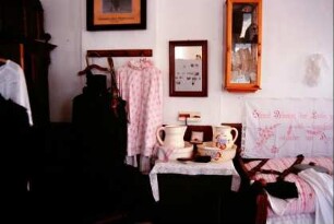 Heimatstube: alte Kleidung, Bett, Waschtisch mit Waschgarnitur
