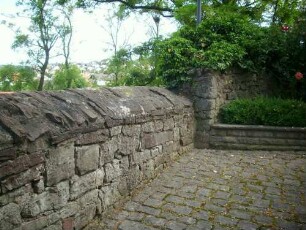 Kirchhof im Westen mit Kirchhofmauer (Wehrgang mit Steinbrüstung im 18 Jh abgetragen und durch Bischofsmützen als Regenschutz ersetzt)