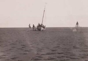 Nordsee, Insel Mellum, Fischerboot bei Ebbe im Wattenmeer, im Hintergrund die Dreikantbake der Vogelschutzinsel Mellum