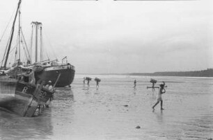 Ebbe : Bagamoyo. Männer löschen Boote bei Ebbe