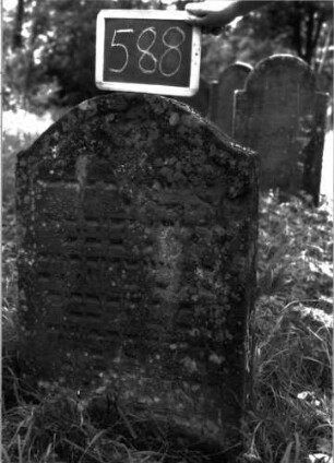 Grabstein 588 (Index: 100102454) Material: Sandstein Zustand: stark verwittert, leicht eingesunken, weitgehender Textverlust Maße HxBxT: 91x58x11 cm Beschreibung: Stele, Konvexbogenabschluss, Schriftfeld eingetieft: Grabstein 588