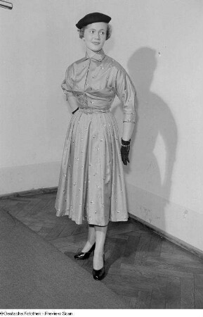 Eine Frau posiert mit Kleid und Hut bei der "Internationalen Messemodenschau", Herbstmesse 1953