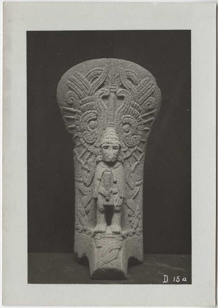 Stone palma with human figure in bird-man disguise. With cap, cape and club in hand. Front of the stone sculpture. Guillermo de Heredia Collection.