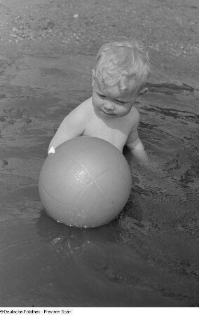 Kleiner Junge, mit einem Ball im Wasser spielend