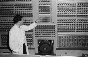 Elektronenrechner auf Röhrenbasis. Mitarbeiter vor der Hardware stehend