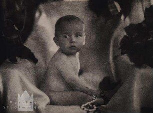 Nacktes Baby auf Decke, in einem Sessel sitzend