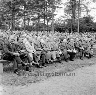 Tag der Deutschen Einheit: Feierstunde: Naturbühne: Bürgerpark: Blick auf Teilnehmer auf Sitzreihen, darunter Kreispräsident Friedrich Hardt, Bürgerworthalter Willy Rosch, Direktor der Theodor-Mommsen-Schule Richard Staberock: hinten Bäume