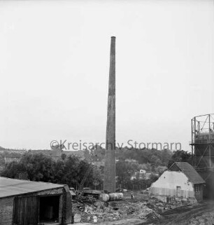 Stadtwerke Bad Oldesloe: Gaswerk: Lübecker Straße: Sprengung des Schornsteins des abgerissenen Kraftwerks: in der Mitte vor Schornstein Bauschutt, Gastank, Lkws: vorn links Gebäudedach: rechts teilweise abgerissenes Gebäude und Gasometer: hinten Gebäude und Bäume: 10. Juni 1971
