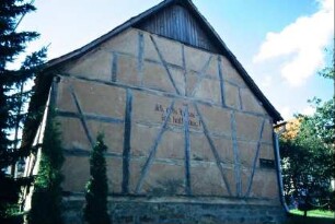 Giebelansicht einer Fachwerkscheune in der Schwarzaer Straße mit Spruch "Ich alt's Haus ich halt aus"