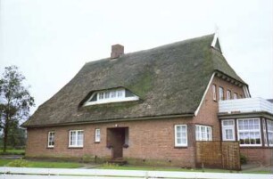 Dorfstraße 22: Bauernhaus mit Reetdach: Traufseite mit Windfang, Eingangstür und breiter Gaube: Giebelseite mit Standerker und Altan