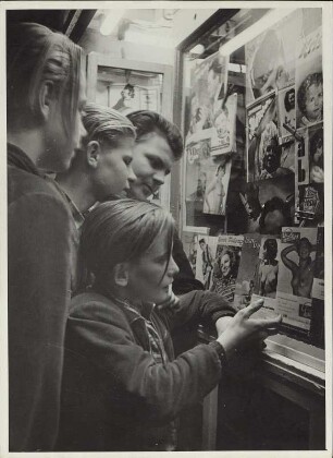 Jugendliche Männer stehen vor dem Schaufenster eines Kiosks