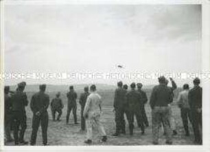 Eine Truppe erwartet ein im Anflug befindliches Flugzeug
