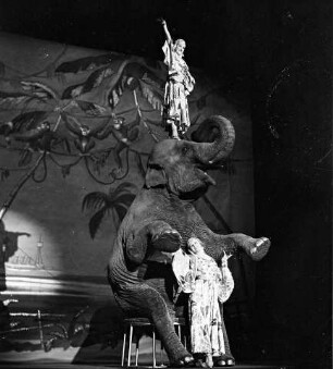 Wintergarten: Althoffs Tanzende Elefanten; Elefant sitzt auf Hocker; Frau zwischen Forderbeinen [eine steht auf Kopf des Elefanten]