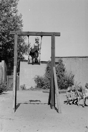 Betriebskindergarten der VEB Stralauer Glaswerke : Kinder auf einem Spielplatz auf einer Schaukel