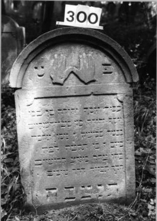 Grabstein 300 (Index: 99803457) Material: Sandstein Zustand: gut Maße HxBxT: 88x56x12 cm Beschreibung: Stele mit verdachtem Rundbogen, profilierter Rand, Giebelfeld Symbolik: segnende Hände Besonderheit: Endreim: Grabstein 300