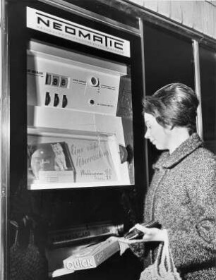 Eine Frau kauft an einem Warenautomat an der Straße ein