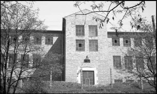 Warburg: Konservenfabrik, Torflügel in Front, Vordergrund Bäume
