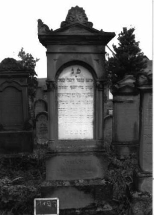 Grabstein 1197 (Index: 100104359) Material: Sandstein, Marmortafel Zustand: gut erhalten, beginnenden Verwitterung Maße HxBxT: 205x64x30 cm Beschreibung: Stele auf getrepptem Sockel, Giebelaufsatz mit Giebel- und Eckakroterien (Blattornamente), eingelassene Schrifttafel mit Rundbogenabschluss, gerahmt von dünnen Säulen mit Blattkapitellen, (vgl. Grabstein der Gattin) Symbolik: Blattornamente: Grabstein 1197