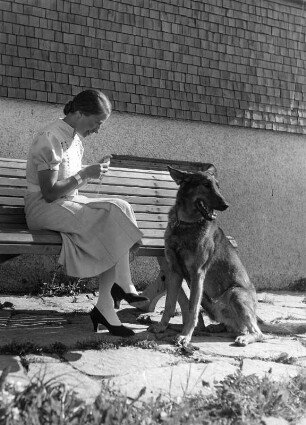 Frau, auf einer Bank sitzend, mit Schäferhund