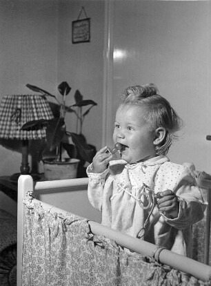 Kinderbilder. Kleinkind in seinem Bettchen stehend